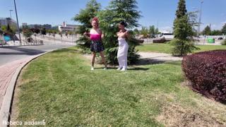 Two girls exposing their breasts to passersby on a dirty street corner